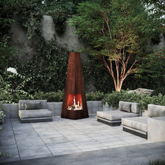 Decorative outdoor Mac Landscape's Zenith Blaze fire pit with a tribal design in a garden setting.