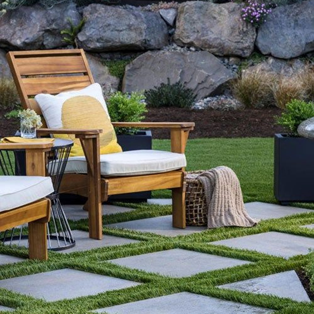 Wooden chair with cushions on a stone patio in a garden setting with artificial grass