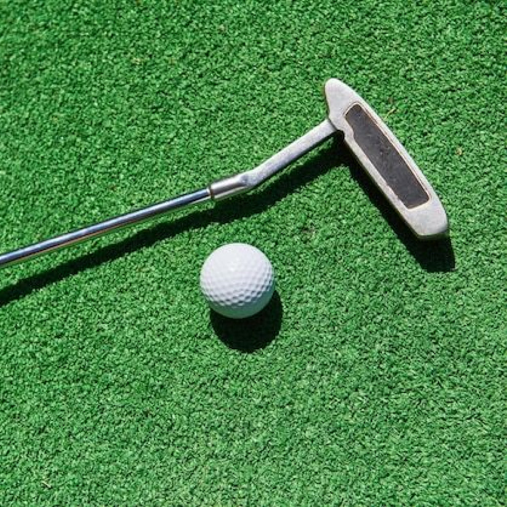 Golf putter and ball on a premium grass putting surface