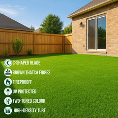 Green artificial grass in a backyard with a house and wooden fence.
