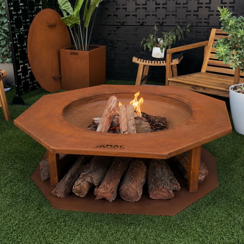Corten Steel King Midus Fire Pit in a modern outdoor entertaining area, featuring a rust-finished octagonal steel fire pit with a wide tabletop surround and integrated firewood storage underneath. Burning logs create a warm focal point, complemented by timber outdoor furniture and contemporary garden planters.