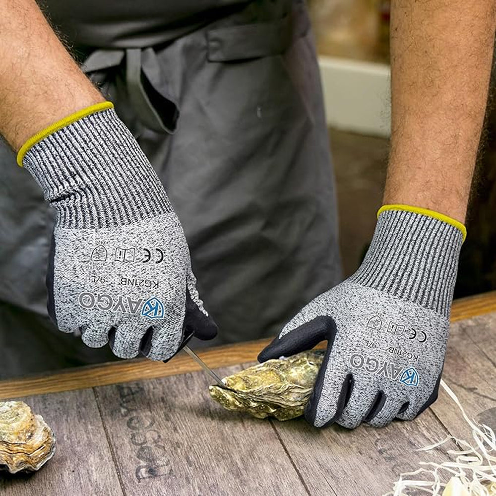 Person wearing gray gloves with yellow accents, working on an oyster.