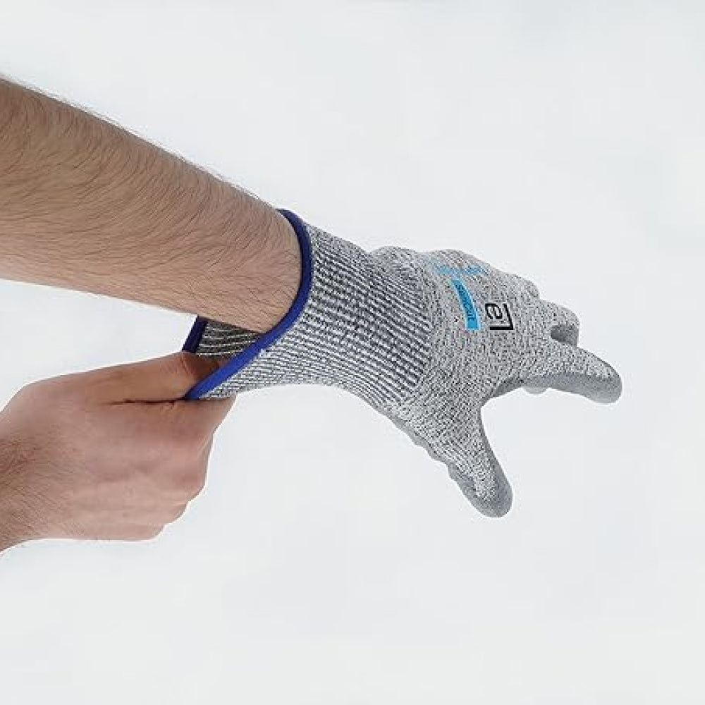 Gray cut-resistant glove with blue trim held by a person on a white background